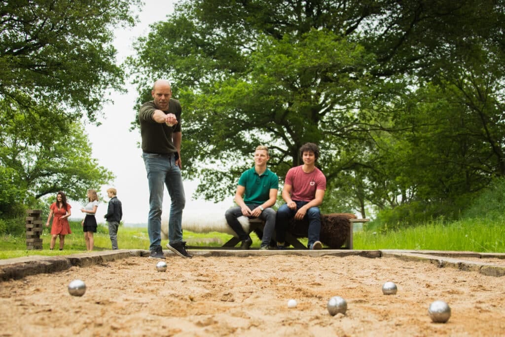 Drietal mensen speelt een spelletje Jeu de Boule tijdens een uitje bij Taribush.