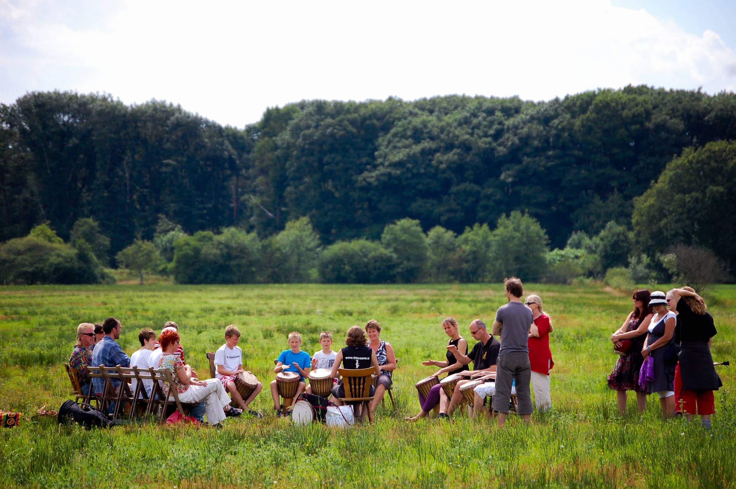 Groep mensen volgt Djembé workshop midden in het veld in de natuur van Drenthe.
