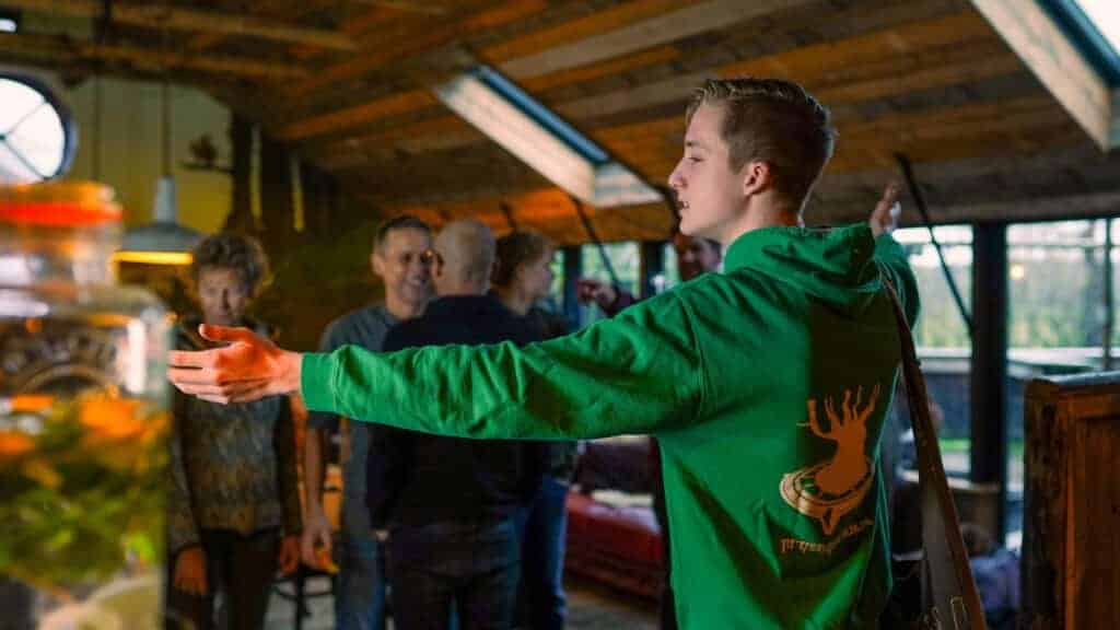 Een spelleider van Taribush in een Taribush trui legt een teambuildingsactiviteit uit tijdens een groepsuitje in de natuur.