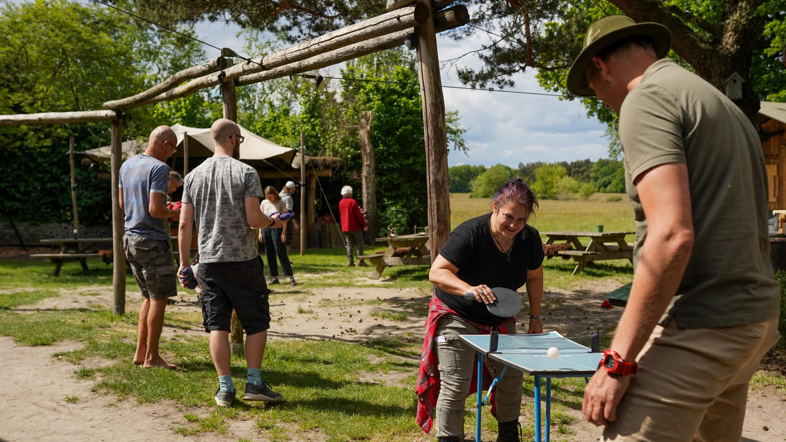 Groep mensen speelt allerlei verschillende spellen van een spelletjesbar in een natuurlijke omgeving tijdens een groepsuitje bij Taribush
